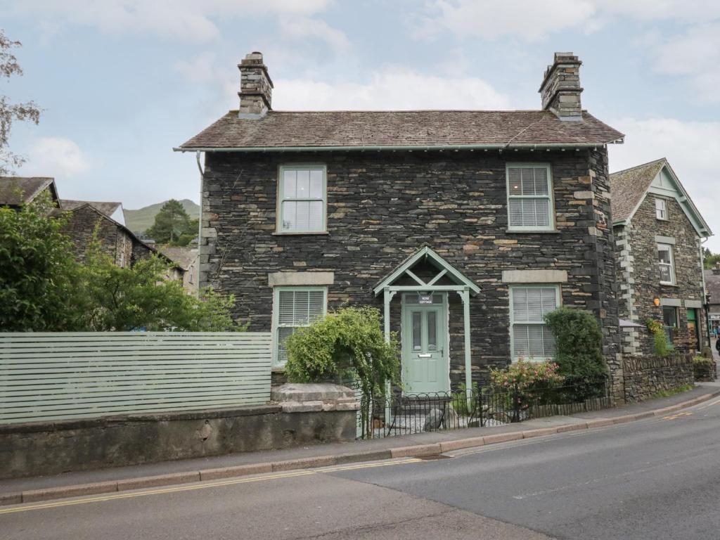 an old brick house with a green door on a street at Rose Cottage in Ambleside