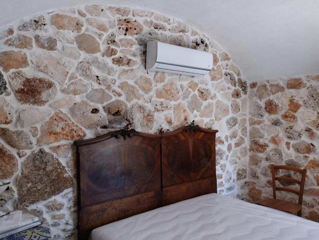 een slaapkamer met een stenen muur en een bed bij Trullo Nicola in Ceglie Messapica