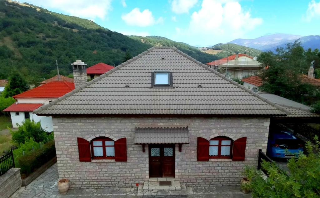 een klein bakstenen huis met rode ramen en bergen bij Lina's Stone House in Kalavrita