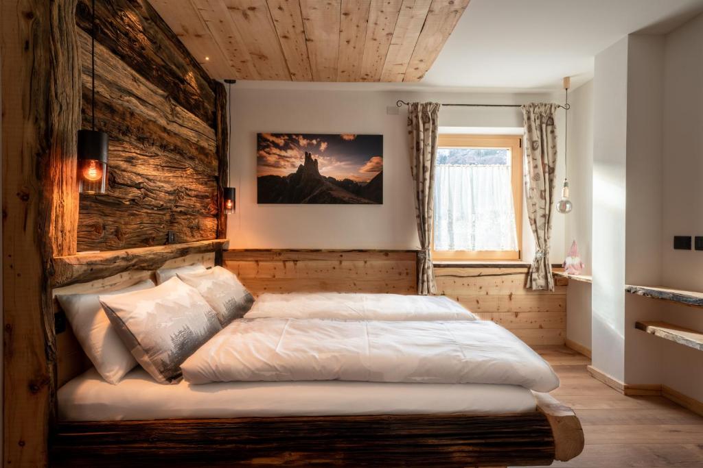 a bed in a room with a wooden wall at Ciasa Marizana in Soraga
