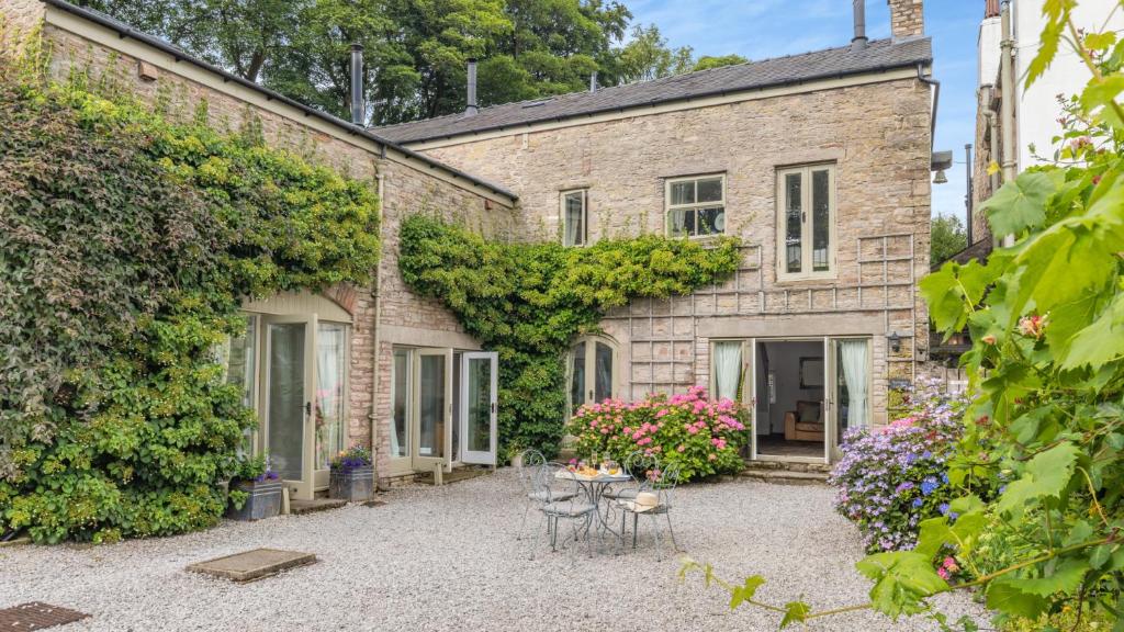 a stone house with a courtyard with chairs and flowers at Woodpecker in Chinley