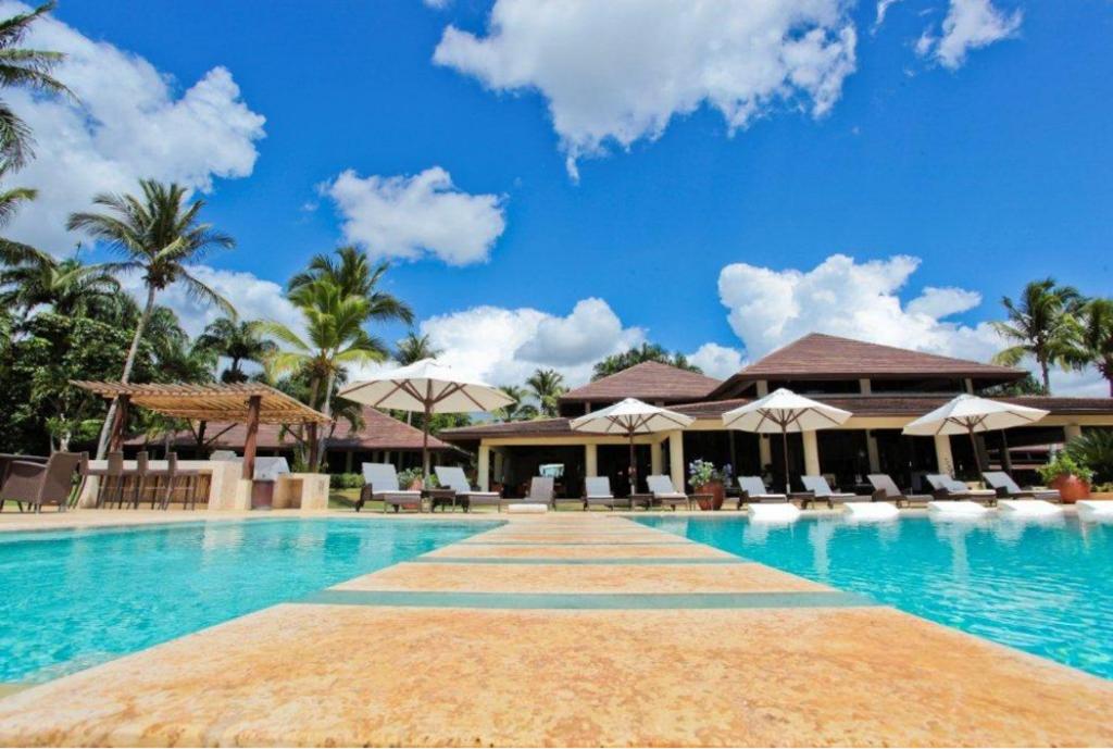 uma piscina no resort com cadeiras e guarda-sóis em Sunny Vacation Villa No 43 em San Rafael del Yuma