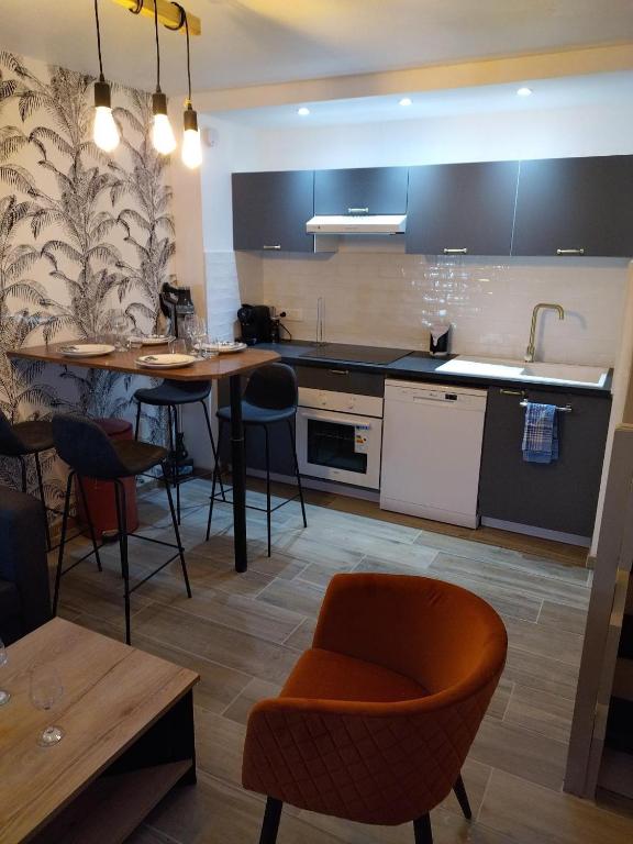 a kitchen with a table and some chairs in a room at Le triplex Côté plage plein Sud in Courseulles-sur-Mer