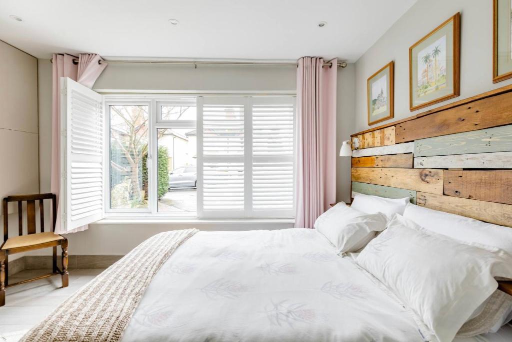 una camera da letto con un grande letto bianco e una finestra di Arlington - private room and en-suite a Woking