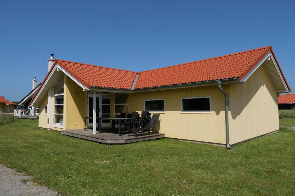 ein kleines gelbes Haus mit einer Terrasse in der Unterkunft Resort 2 Ferienhaus Typ D 28 in Großenbrode