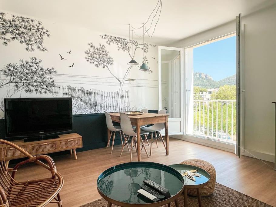 Una sala de estar con un televisor y una mesa con sillas. en Panisse - Parking - Clim - Wifi, en Cassis