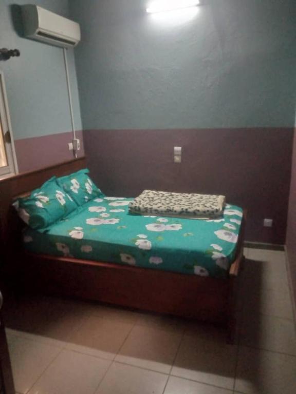Cama pequeña en habitación con sábana verde en Grace and favour guest house, en Douala