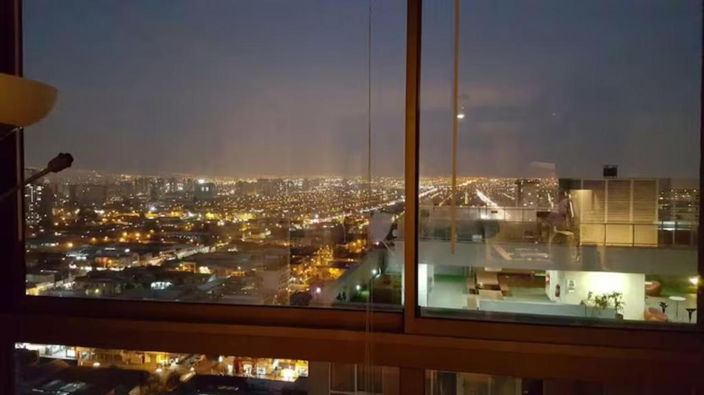 una ventana con vistas a la ciudad por la noche en Departamento Carmen & Argomedo, en Santiago