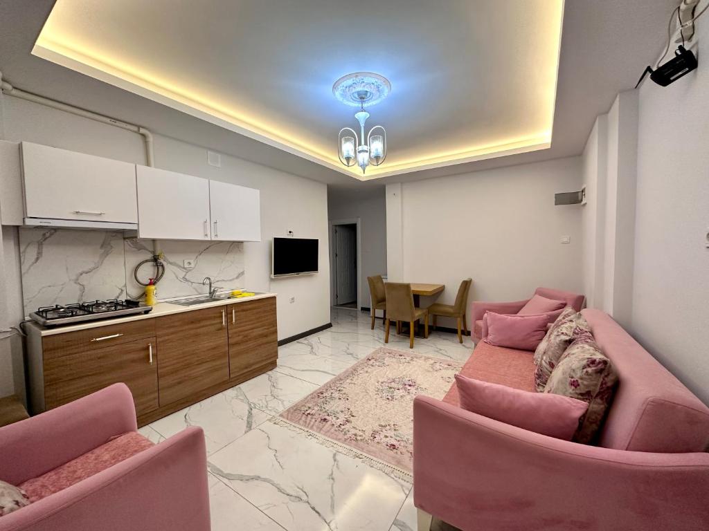 ein Wohnzimmer mit einem rosa Sofa und einer Küche in der Unterkunft Mira Suite Apart in Trabzon