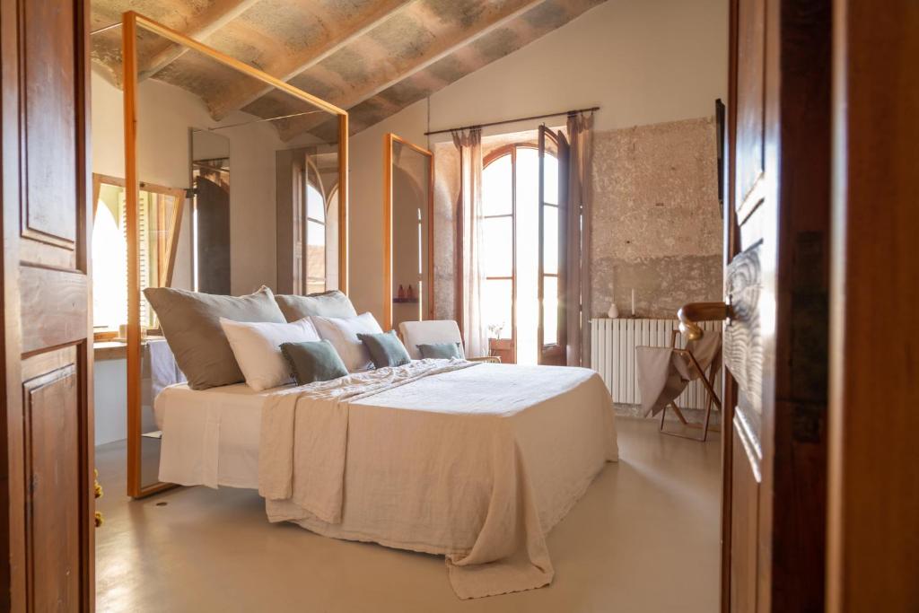 1 dormitorio con 1 cama grande con sábanas y almohadas blancas en Can Moio Turismo de Interior, en Montuiri