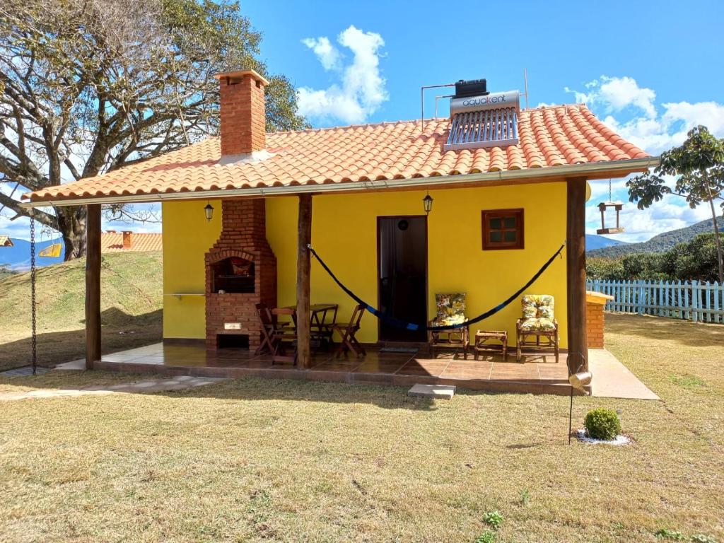 a small yellow house with a roof at Chalé Mirante Da Guapiara in Aiuruoca