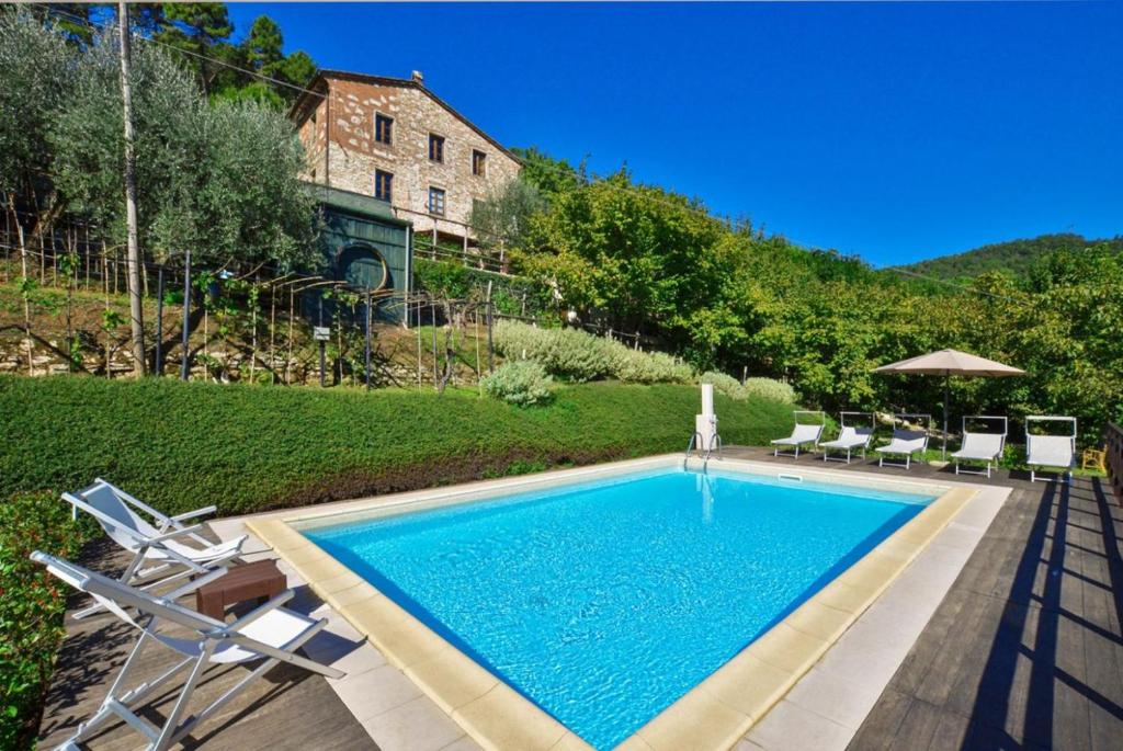 a swimming pool with chairs and a house at Villa Casale Di Rosa in Lucca