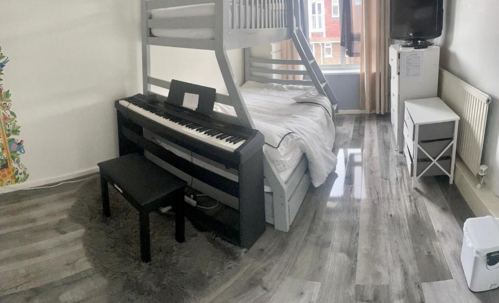 a bed with a piano and a chair in a room at Cosy Room by Excel, Emirates Cable Car, 02Arena in London