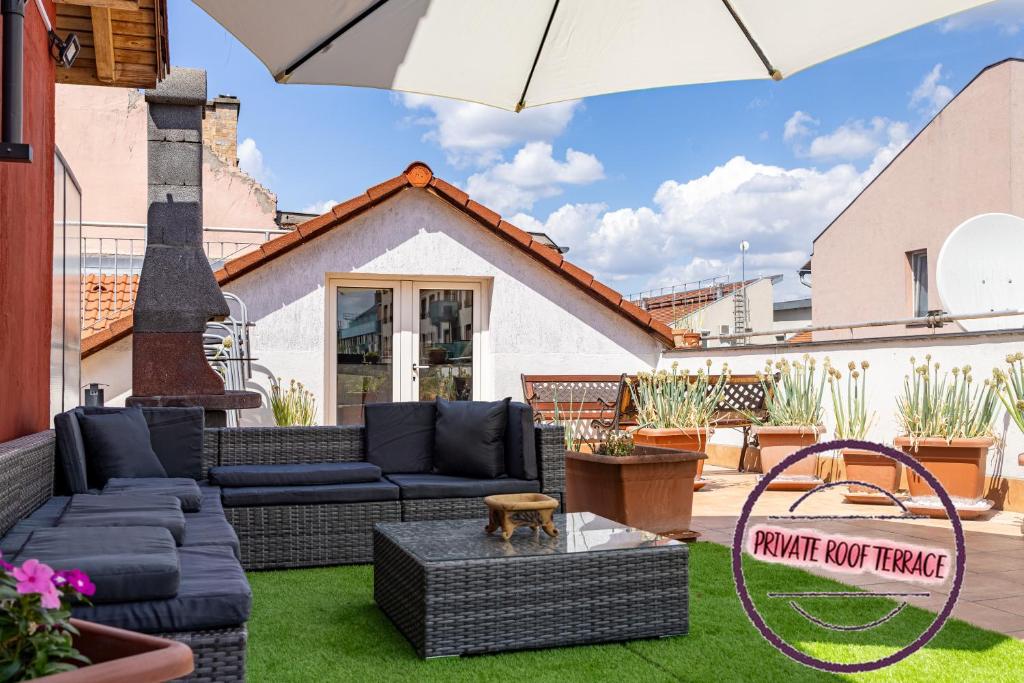 a patio with a couch and an umbrella at Center PENTHOUSE apartment - HUGE TERRACE and FREE PARKING - Tram/Metro - AC in Budapest