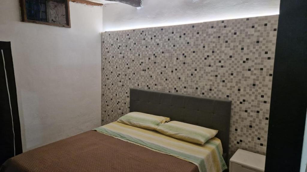 Ce lit se trouve dans une chambre dotée d'un mur carrelé. dans l'établissement Chez Taii, à Serralta