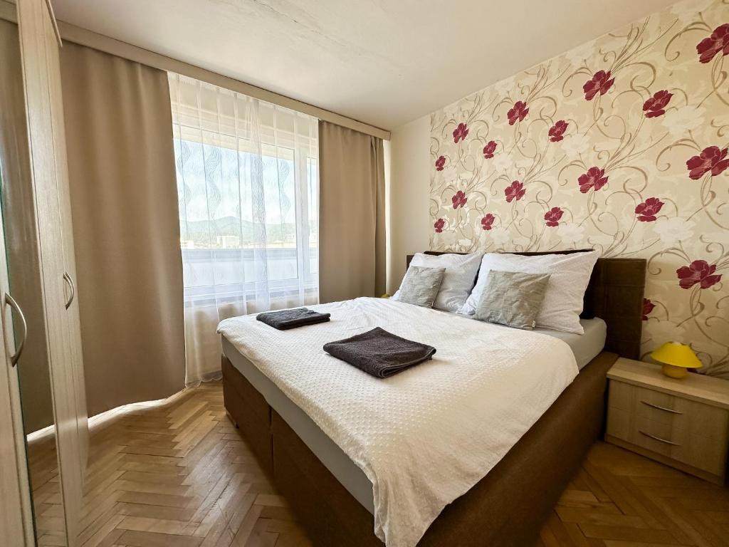 1 dormitorio con 1 cama grande y papel pintado con motivos florales en Apartmán Simcity 2 en Banská Bystrica