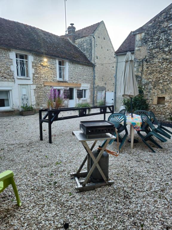 a patio with a grill and a table and an umbrella at La Feuillette in Maligny