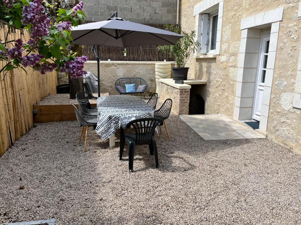 a patio with a table and chairs and an umbrella at Gîte Au Coeur d’Azay in Azay-le-Rideau