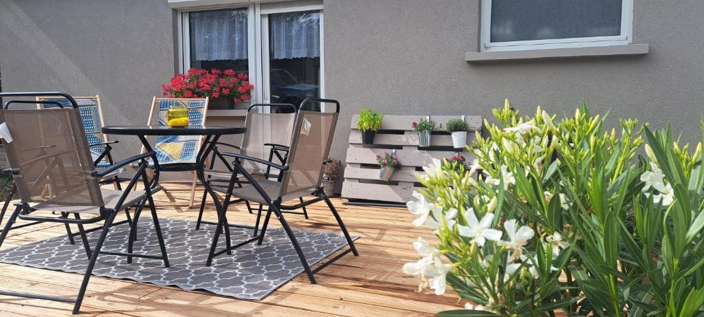eine Terrasse mit Stühlen, einem Tisch und einigen Blumen in der Unterkunft le refuge du bonheur in Bitche