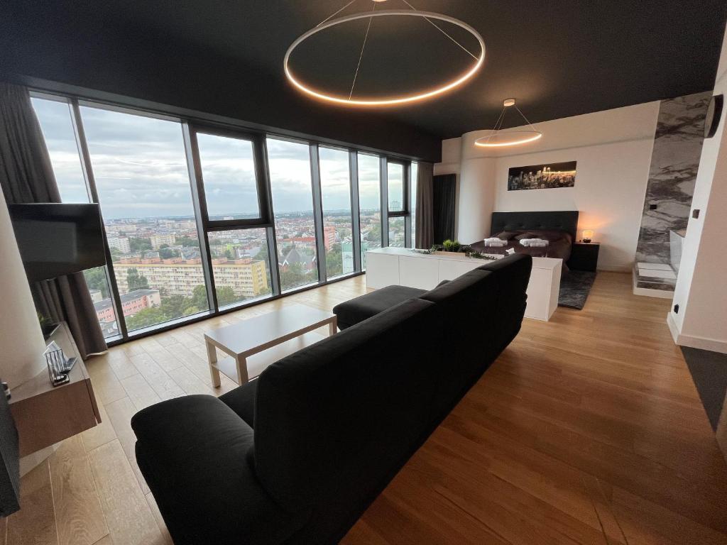 uma sala de estar com um sofá e algumas janelas em Hanza Tower - Luxurious Apartment 60m2 - 15th Floor City View em Szczecin