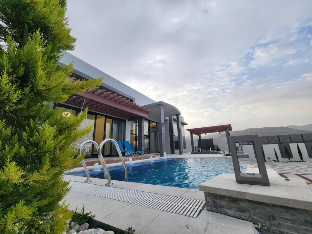 a villa with a swimming pool and a house at Skylight chalet in Nizwa