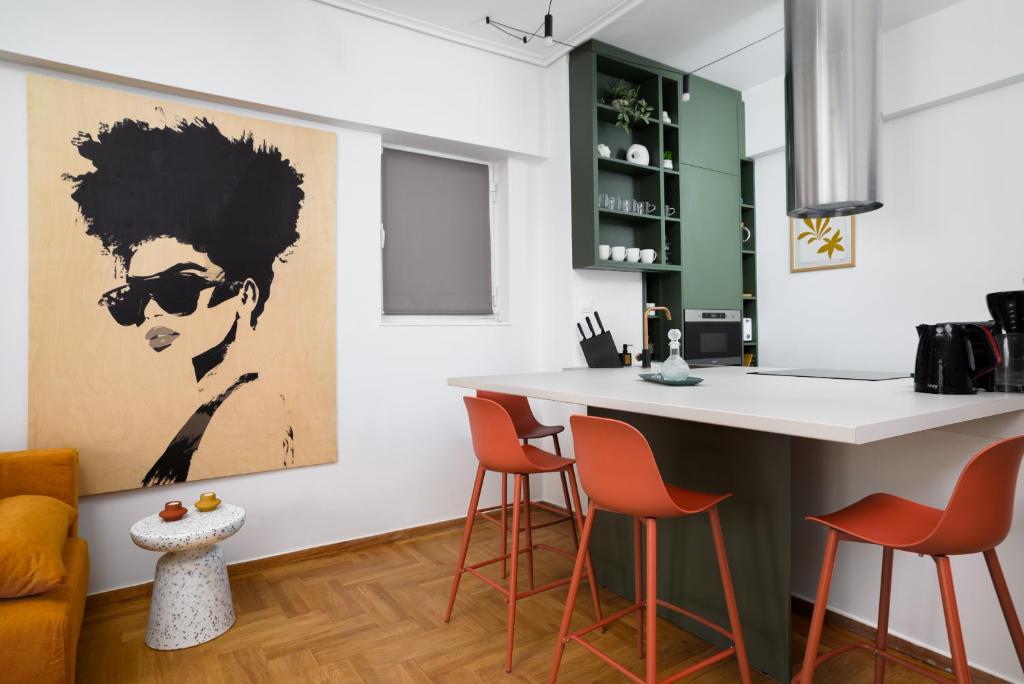 eine Küche mit einer Bar mit orangefarbenen Stühlen und einem Gemälde in der Unterkunft H Experience - Funky 1BD apartment in vibrant Nea Smirni in Athen