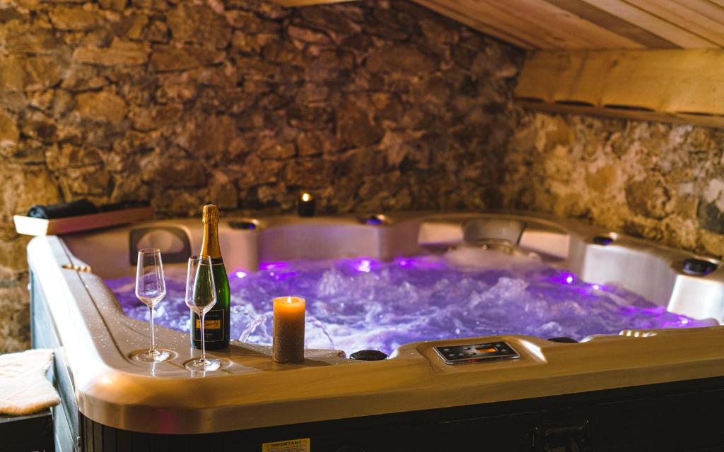 a hot tub with a bottle of wine and two glasses at La Ferme de Beauregard SPA -LANARCE 07660 - jacuzzi et sauna in Lanarce