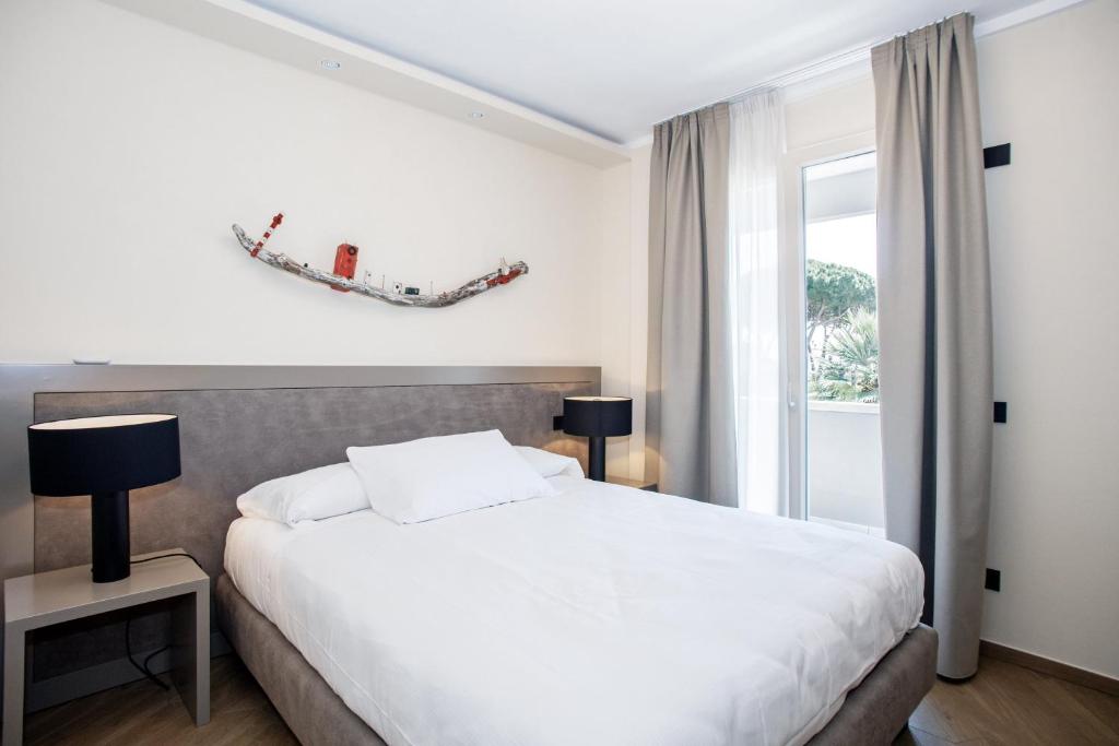 a bedroom with a white bed and a window at Hotel Barcarola 2 in Marina di Campo