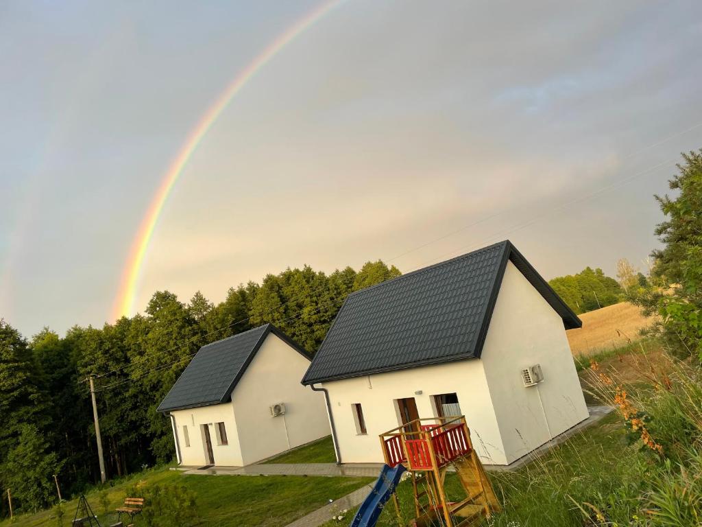 dos casas blancas con un arco iris en el fondo en Przystań nad Legą en Olecko