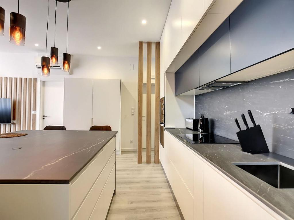 une cuisine avec des placards blancs et un comptoir noir dans l'établissement O Flamingo Apartments, à Ovar