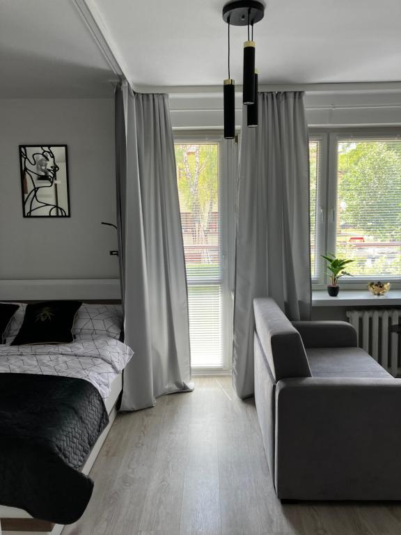 um quarto com uma cama, um sofá e uma janela em Charming Apartament em Plock