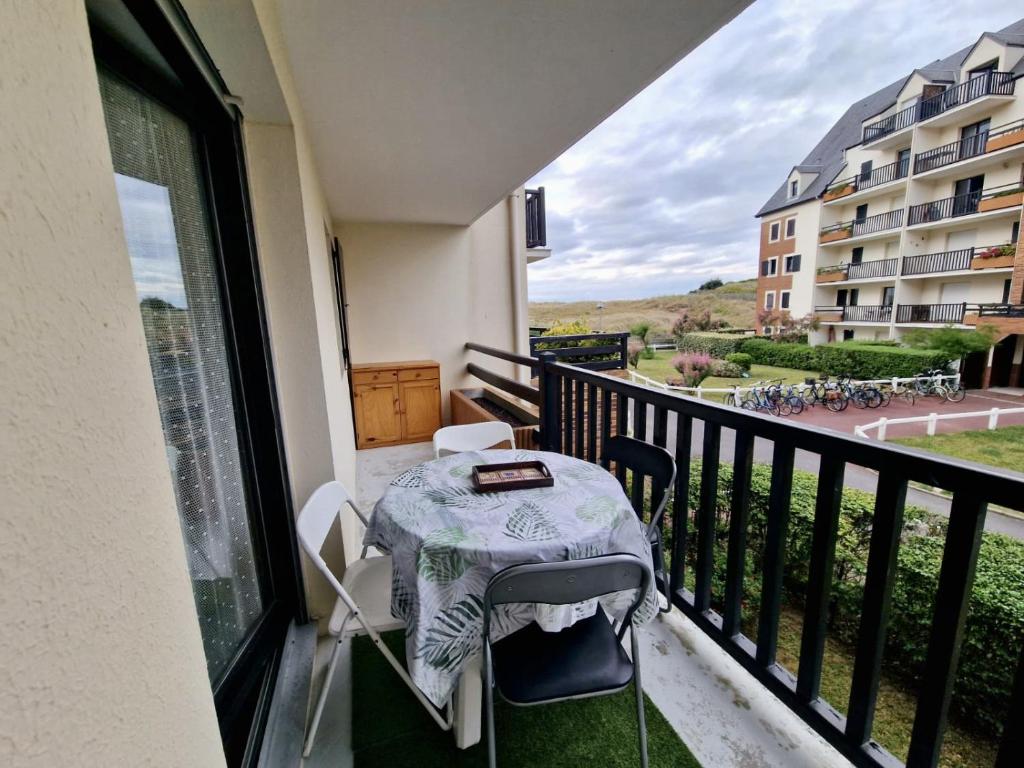 d'un balcon avec une table et une vue sur un bâtiment. dans l'établissement Les pieds dans le sable, à Cabourg