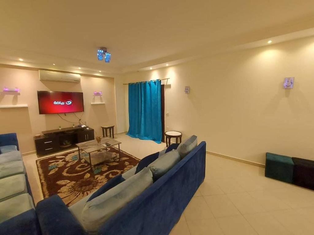 sala de estar con sillas azules y TV de pantalla plana en شقق سكنيه للايجار en El Cairo