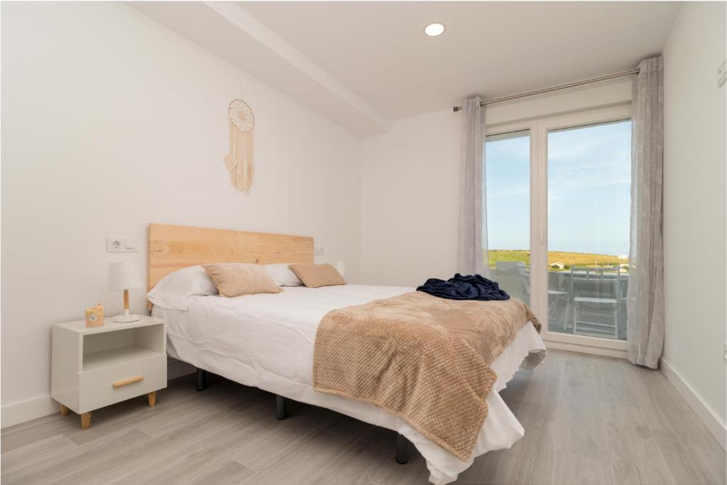 a white bedroom with a bed and a window at REFUGIO DEL PESCADOR Apartamento Maruca in Santander