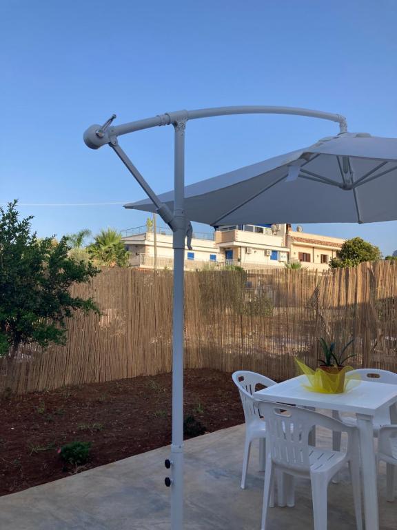 a white umbrella sitting next to a table and chairs at Passalacqua House in Cinisi