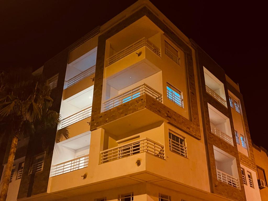 un edificio giallo alto con finestre di notte di ABC Family appart a Saïdia