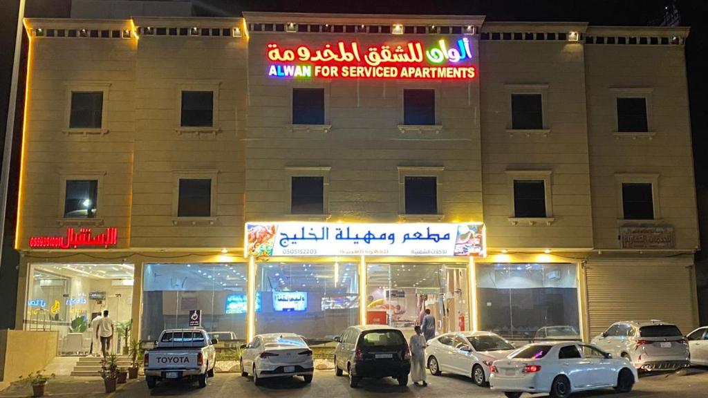 budynek z samochodami zaparkowanymi przed nim w obiekcie Alwan apartment hotel w mieście Chamis Muszajt