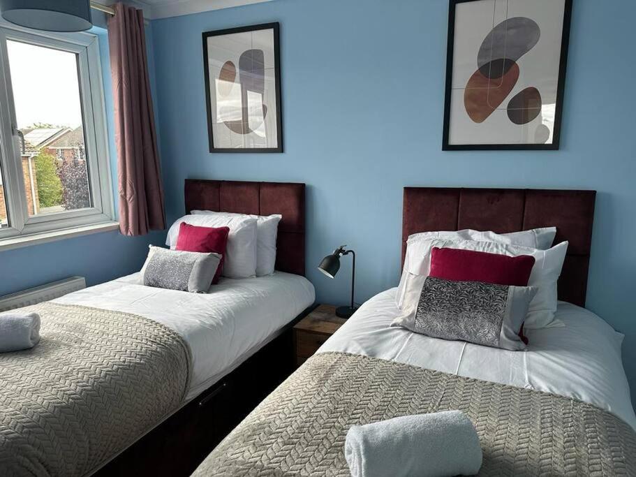 皇家伍頓巴西特的住宿－Tennyson House - 3 Bedroom House for Families, Business Travellers, Contractors, Free Parking & Wifi, Nice Garden，卧室设有两张床铺和蓝色的墙壁