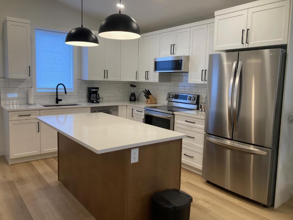 a kitchen with white cabinets and a stainless steel refrigerator at Signature Suites By Oasis Corporate Rentals in Grande Prairie