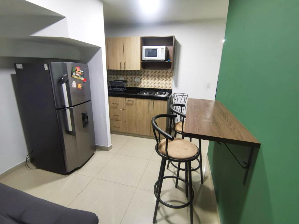 cocina con nevera negra y 2 taburetes en Andaliving Campo Valdes Apartamento, en Medellín