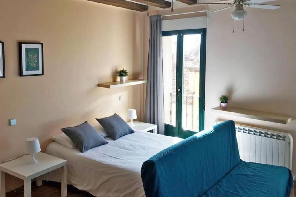 um quarto com uma cama, um sofá e uma janela em Estudio en Centro de Segovia 2 em Segóvia