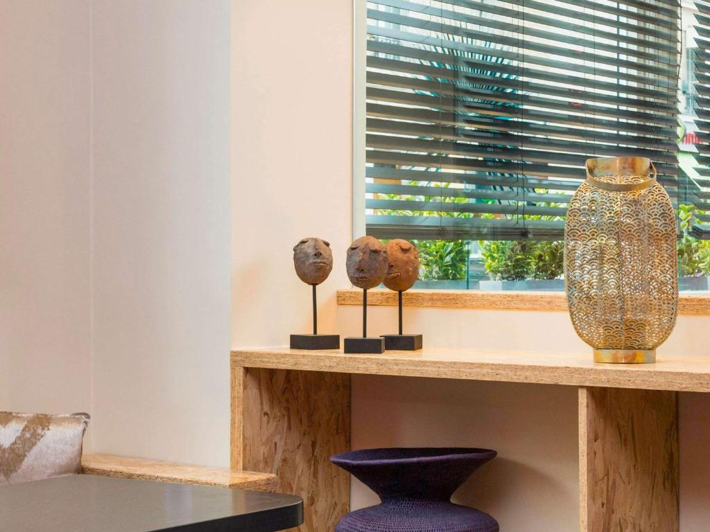 a shelf with three vases on it next to a window at ibis Styles Paris Boulogne Marcel Sembat in Boulogne-Billancourt