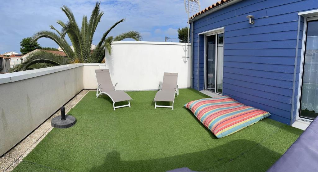 une cour arrière avec une pelouse avec des chaises et une couverture dans l'établissement Idéal famille, maison neuve climatisée à 7 mn à pieds plage Minimes, à La Rochelle