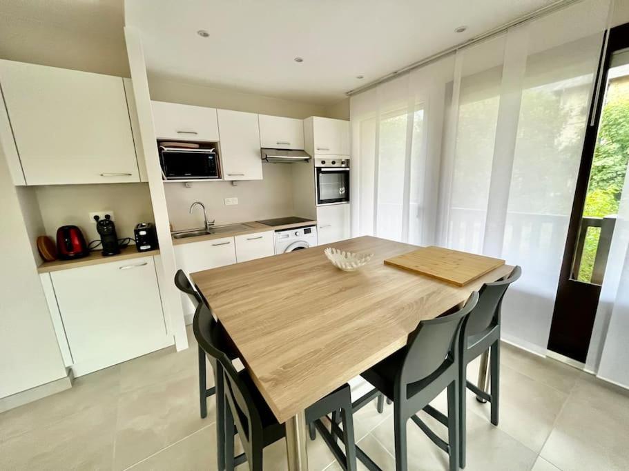 a kitchen with a wooden table and black chairs at Vacances paradisiaques à la plage in Deauville