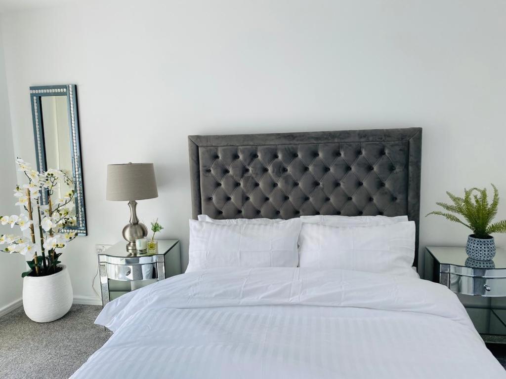 ein Schlafzimmer mit einem weißen Bett mit einem schwarzen Kopfteil in der Unterkunft Modern, Stylish and Central Home in Manchester