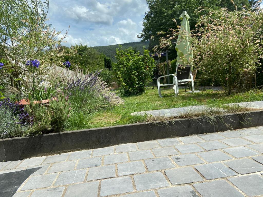 un jardín con una silla en el césped y flores en gite le CARMEL en Fumay