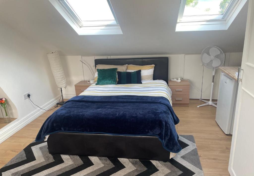 - une chambre avec un grand lit et une couverture bleue dans l'établissement Spacious loft space with private en-suite bathroom, à Londres