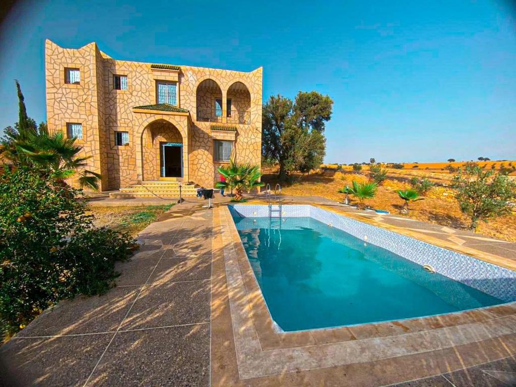 a stone house with a swimming pool in front of it at استمتع بالإقامة في فيلا أحلامك في مدينة الصويرة، in El Khemis des Meskala