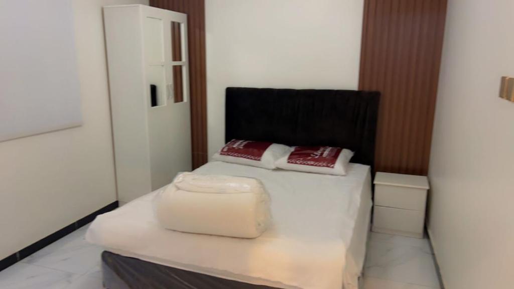 1 dormitorio con cama blanca y silla negra en شاليه سما بارك, en As Sayl aş Şaghīr