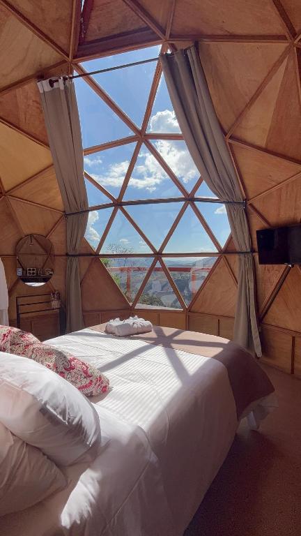 a bedroom with a large window in a yurt at Cabanas Bela Vista in São Bento do Sapucaí